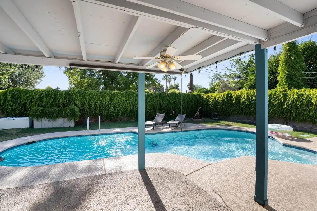 This exterior image showcases a sparkling swimming pool surrounded by lounge chairs and lush greenery, suggesting both recreation and relaxation. The inviting setup is perfect for cooling off after outdoor adventures and provides a taste of the sunny, laid-back Arizona lifestyle.