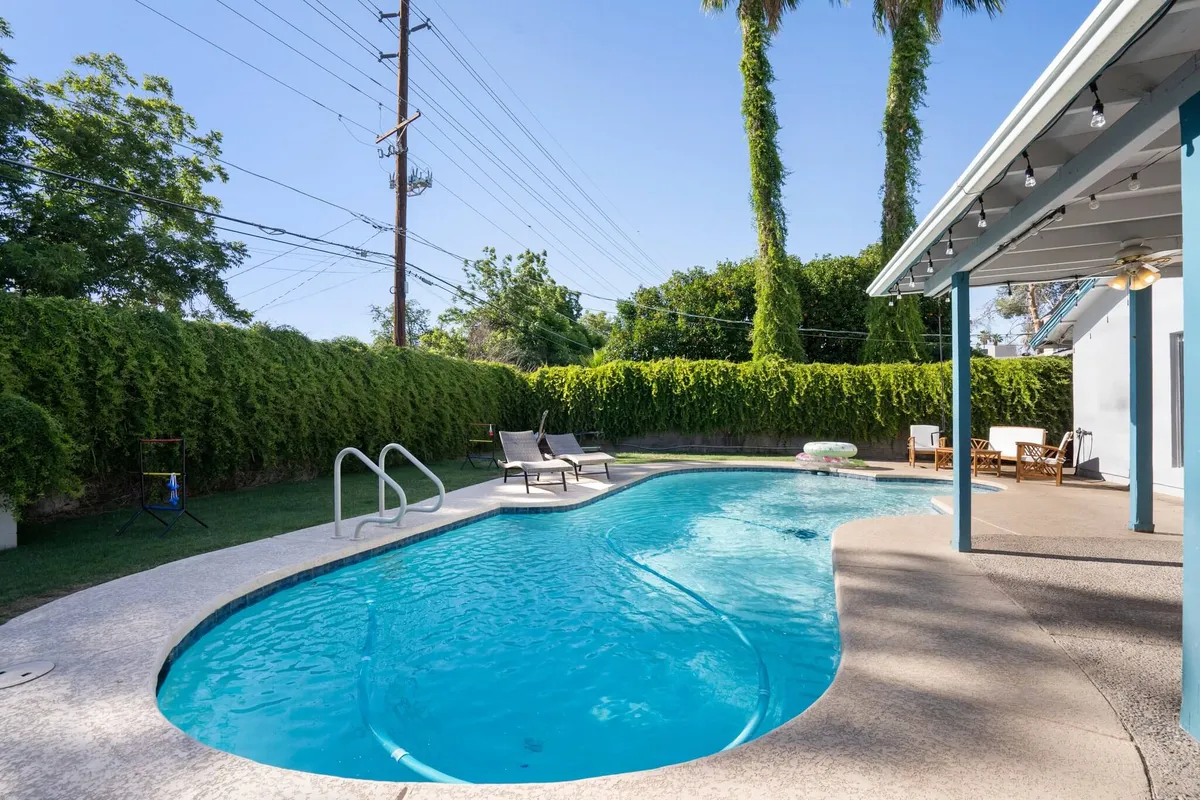 This image captures a sparkling swimming pool surrounded by inviting lounge chairs and lush greenery. The outdoor seating area suggests a space for family relaxation and fun under the sun.