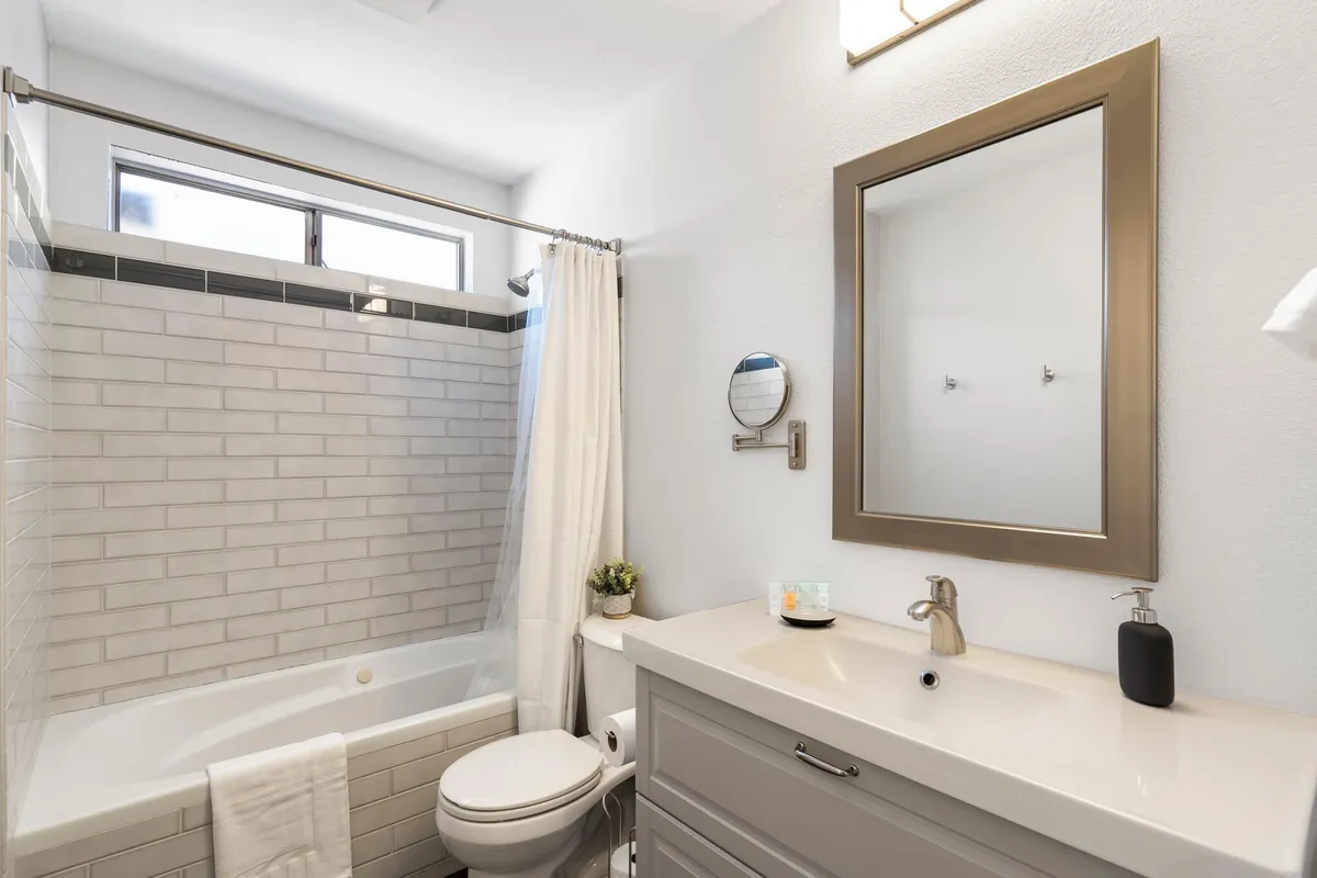 A modern bathroom featuring a standalone bathtub, a sleek sink with a mirror, and a soft shower curtain. The space feels fresh and serene, offering a soothing environment for bathing and personal care routines.