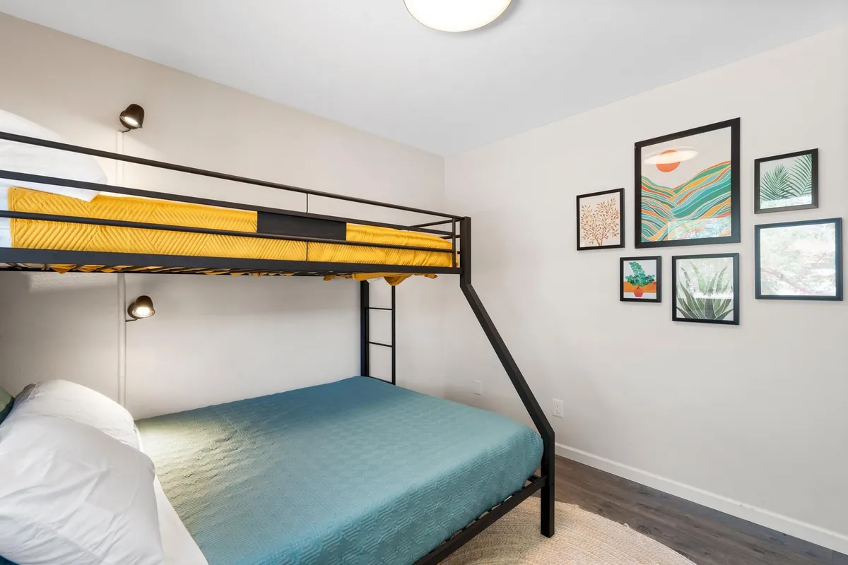 A playful yet inviting bedroom designed for kids or groups, with a bunk bed, cheerful wall art, and a patterned rug. The space radiates comfort and a touch of whimsy—perfect for sleepovers or shared moments.